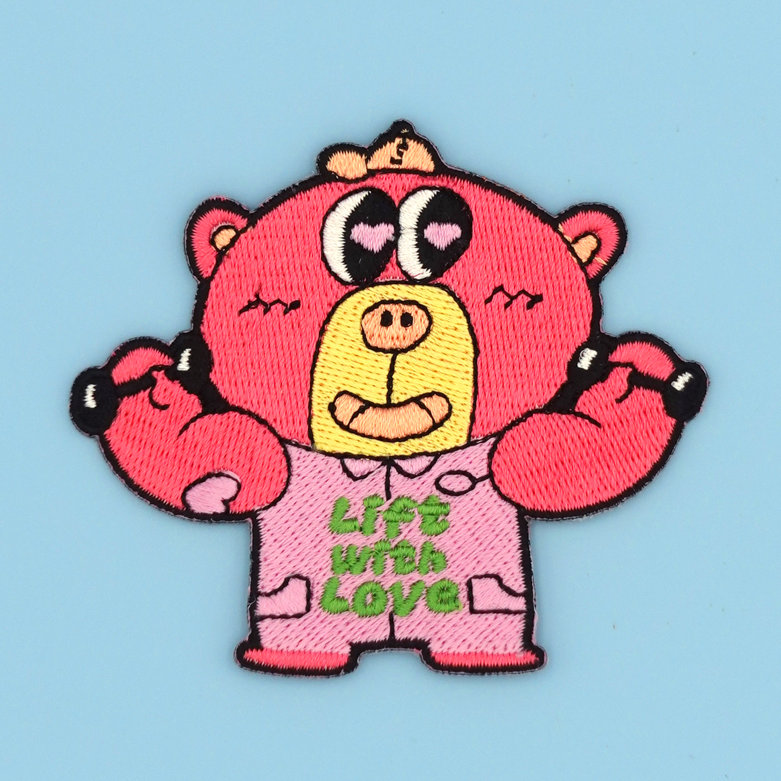 Embroidered pink cartoon bear patch/sticker with 'Lift with Love' text on a light blue background