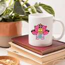 White mug with a pink cartoon bear character design on a stack of books with plants in the background