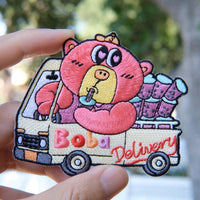 Colorful cartoon character patch held by a hand with a blurred natural background
