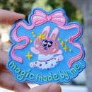 Colorful magical ballet embroidery patch held by a hand with a blurred natural background.
