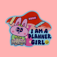 Planner Girl vinyl sticker featuring a cute pink bunny reading a planner and the phrase "I am a planner girl" in bold letters, designed by SmallHappinessLA