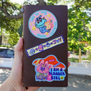 Brown notebook with colorful stickers held outdoors