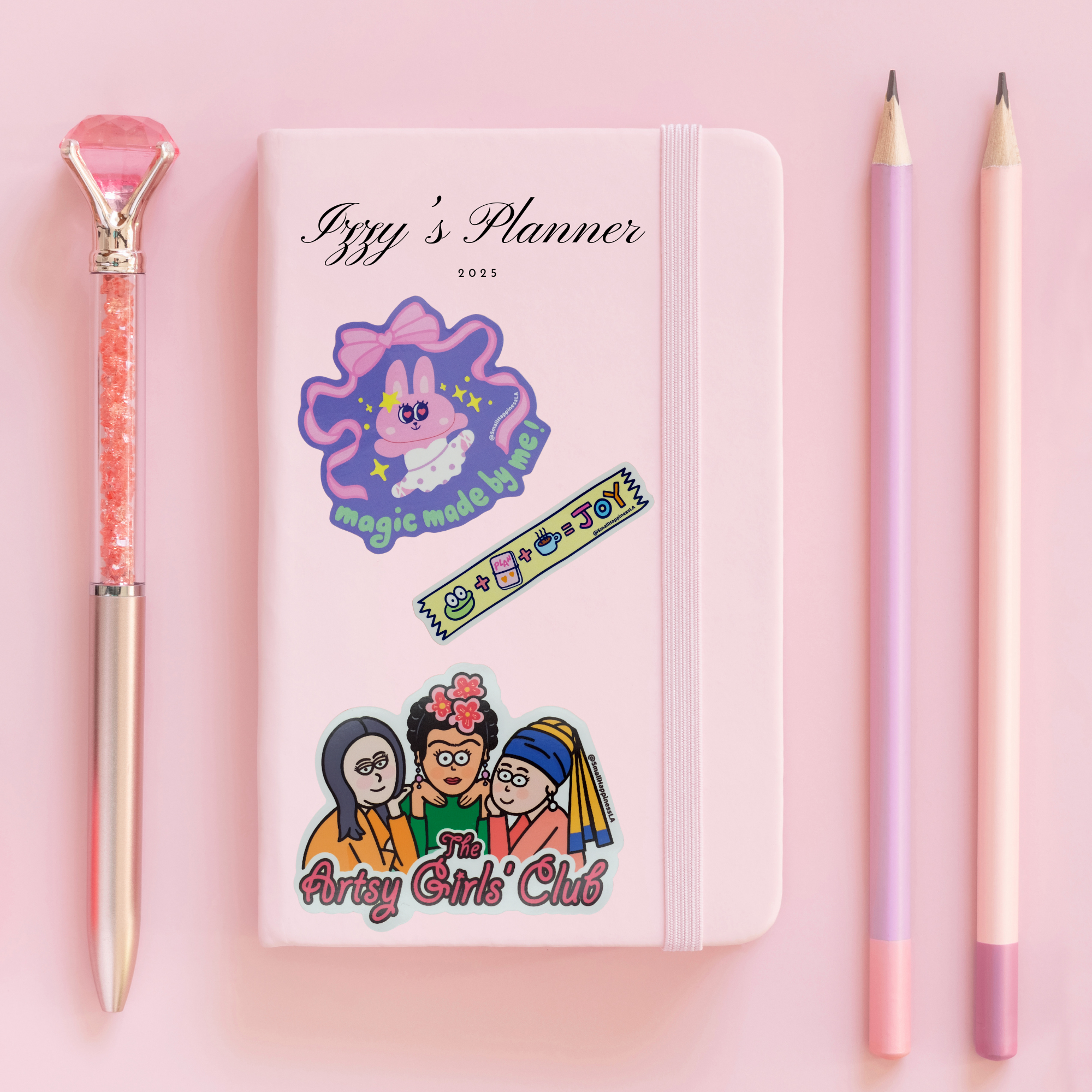 Planner book with stickers designed by SmallHappinessLA and pencils on a pink background