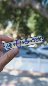 Video of Mochi's Washi Tape embroidery patch held in hand, showing size, texture, stitching details, and fabric under sunlight.
