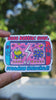 Boss Battle Frog vinyl sticker featuring two cartoon frogs battling on a handheld gaming console screen with the words “Boss Battle: Over” and “Freedom Unlocked” in bold, colorful text, held by hand in natural day light