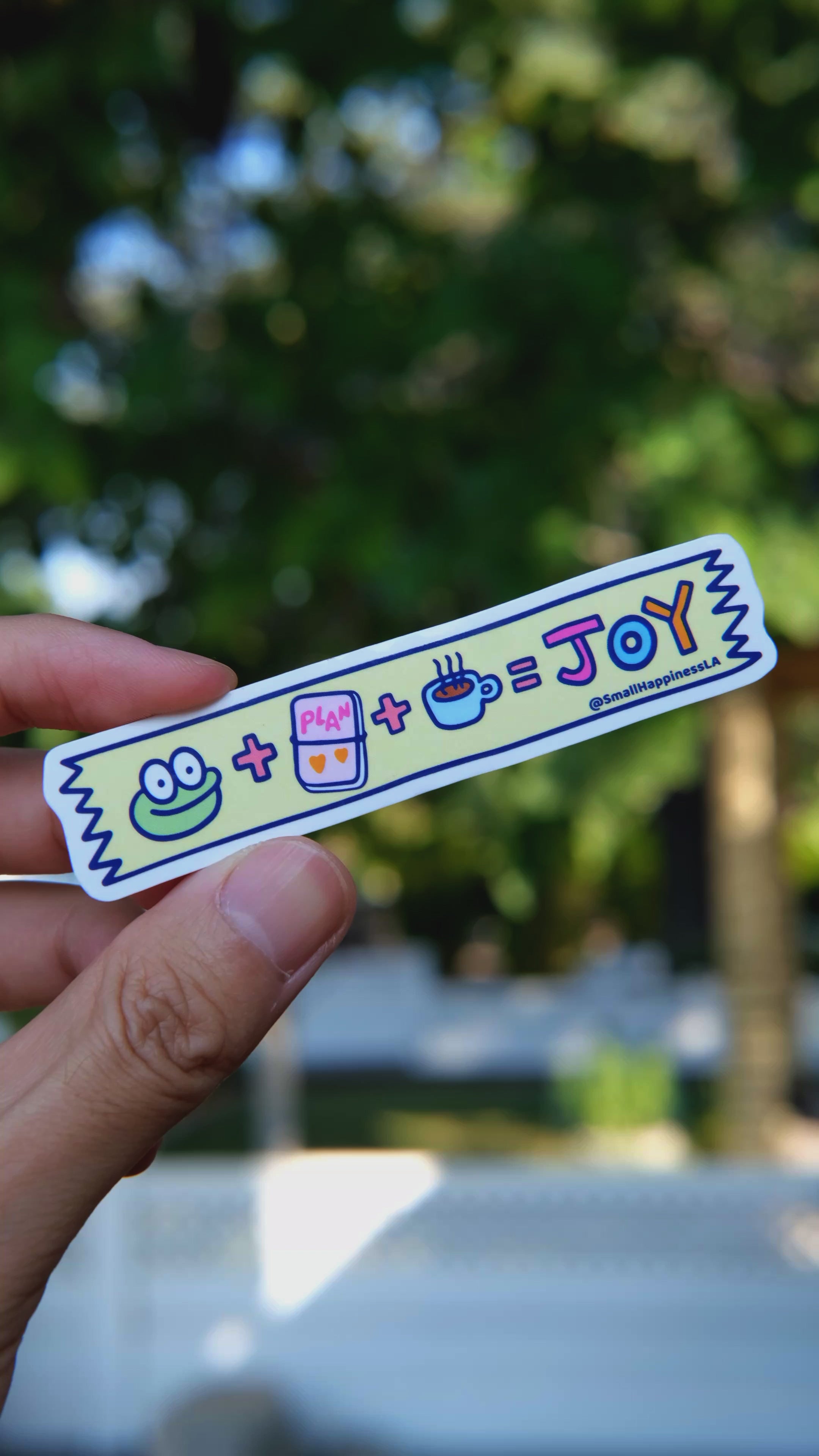 Mochi’s Washi Tape vinyl sticker with Mochi the frog, planner, and coffee design held outdoors in natural light, by SmallHappinessLA