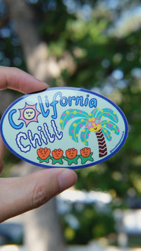 California Chill vinyl sticker with palm tree and flowers design, held by hand in natural daylight