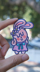 Video of Self-love Bunny embroidered patch held in hand, showing size, texture, stitching details, and fabric under sunlight.

