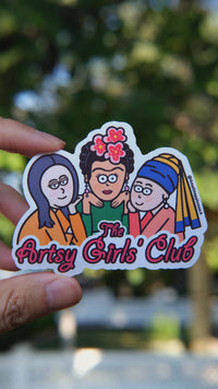 Artsy Girls Club vinyl sticker featuring cartoon versions of iconic women artists, including Mona Lisa, Frida Kahlo, and Girl with a Pearl Earring, on a pink background held by hand in natural day light